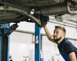 мужчина механик смотрит подвеску у автомобиля