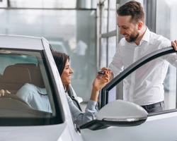 Девушка сидит в новом автомобиле мужчина подает ей ключи