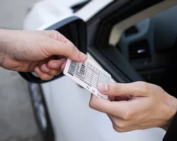 мужская рука передает водительские права водителю на фоне белой машины