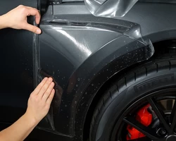 Руки мастера клеят защитную пленку на автомобиль