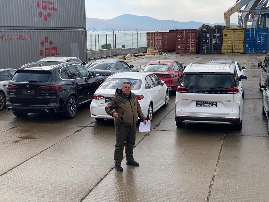 Максим Мирончук мужчина на фоне автомобилей в порту контейнеры