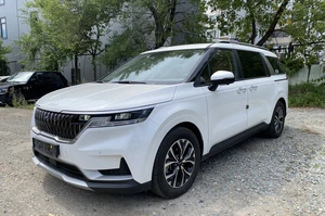 киа карнивал 4 белого цвета на фоне деревьев