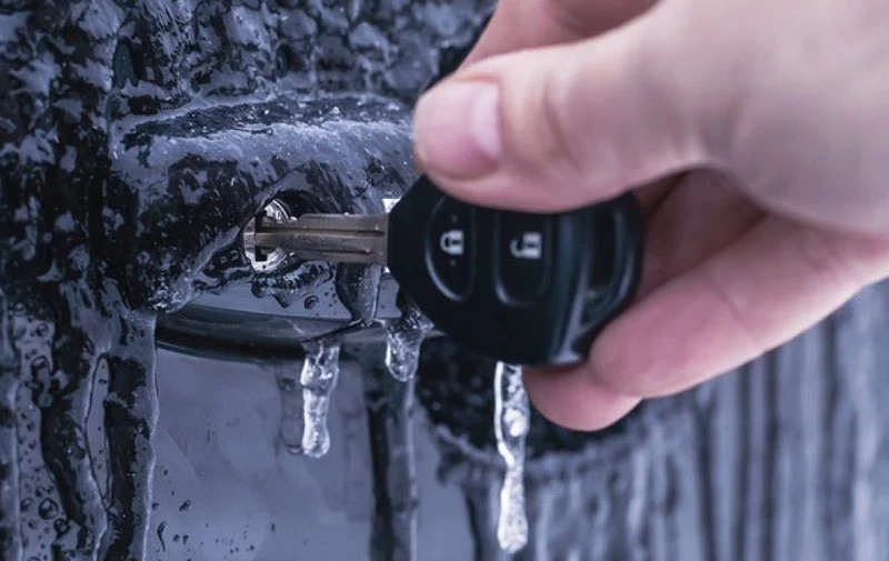 Рука с автомобильным ключом во льду