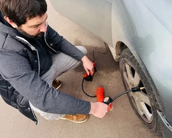 мужчина качает колесо компрессором в осенней куртке