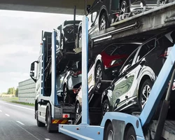 синий автовоз загруженный машинами едет по трассе