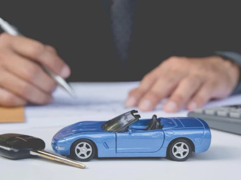 Голубой автомобиль и ключ лежит на столе, мужчина подписывает документы