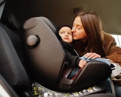 Девушка целует ребенка в автокресле