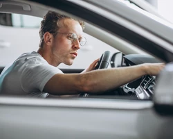 Мужчина в очках сидит за рулем