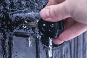 Рука с автомобильным ключом во льду