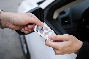 мужская рука передает водительские права водителю на фоне белой машины