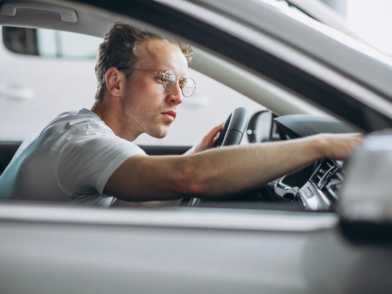 Мужчина в очках сидит за рулем