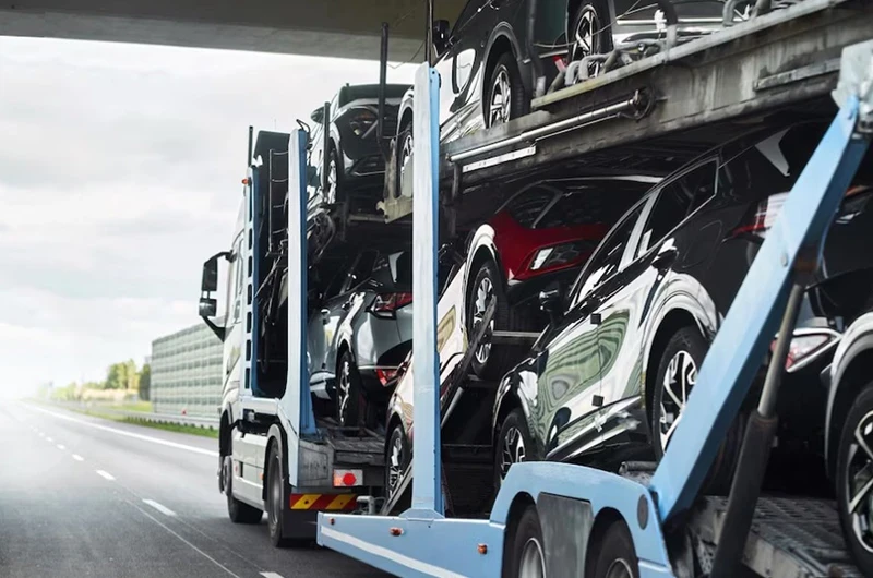 синий автовоз загруженный машинами едет по трассе