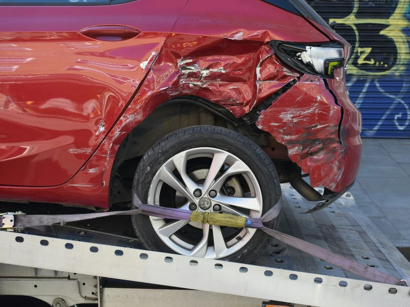 красный автомобиль битый стоит на эвакуаторе