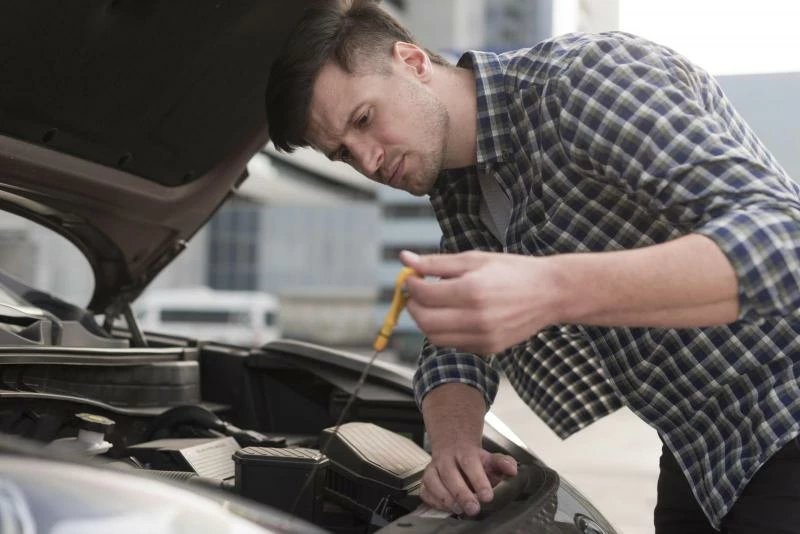 мужчина проверяет уровень масла в автомобиле