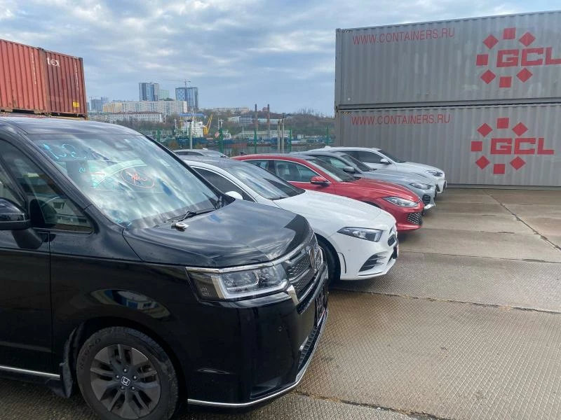 Автомобили стоят в ряд рядос с контейнерами серыми мангистика логистика