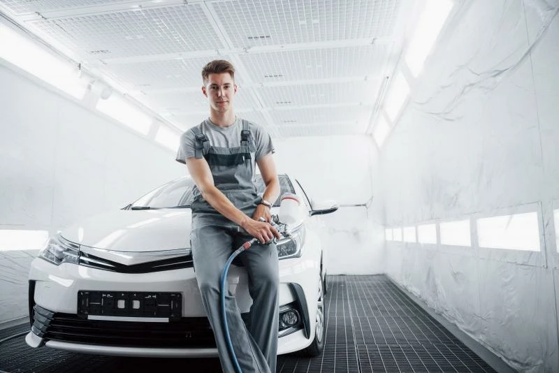 мужчина автомаляр сидит на авто 