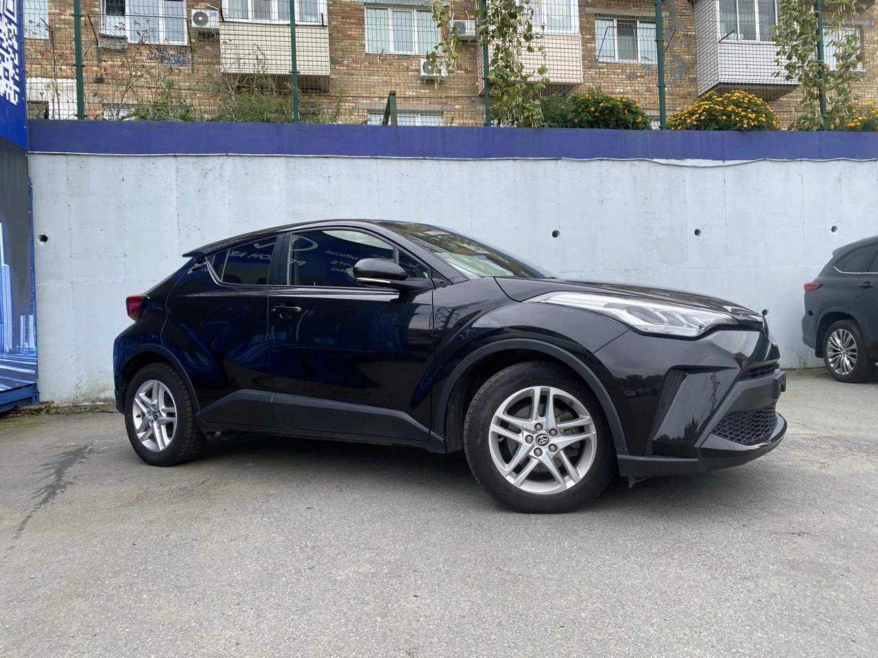 toyota chr черного цвета стоит на фоне дома
