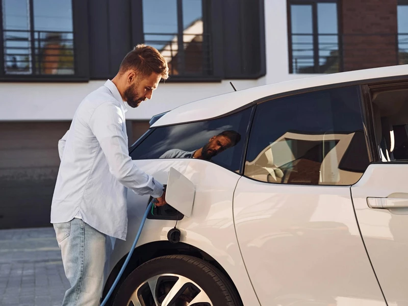 Парень заправляет белый автомобиль