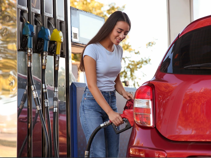 Девушка заправляет бензином красный автомобиль