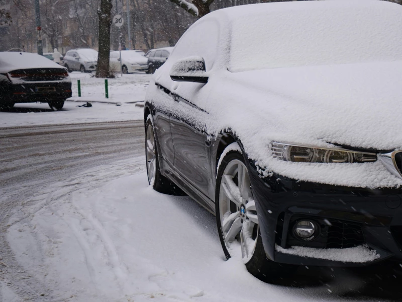 автомобиль стоит заснеженный зимой во дворе 