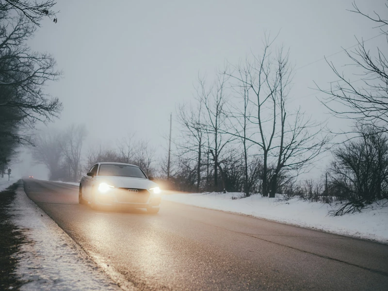 ауди едет по зимней дороге фары включены