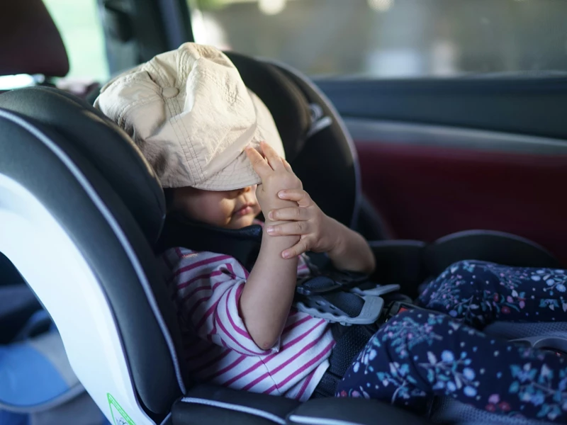 ребенок в панаме в детском кресле в автомобиле 