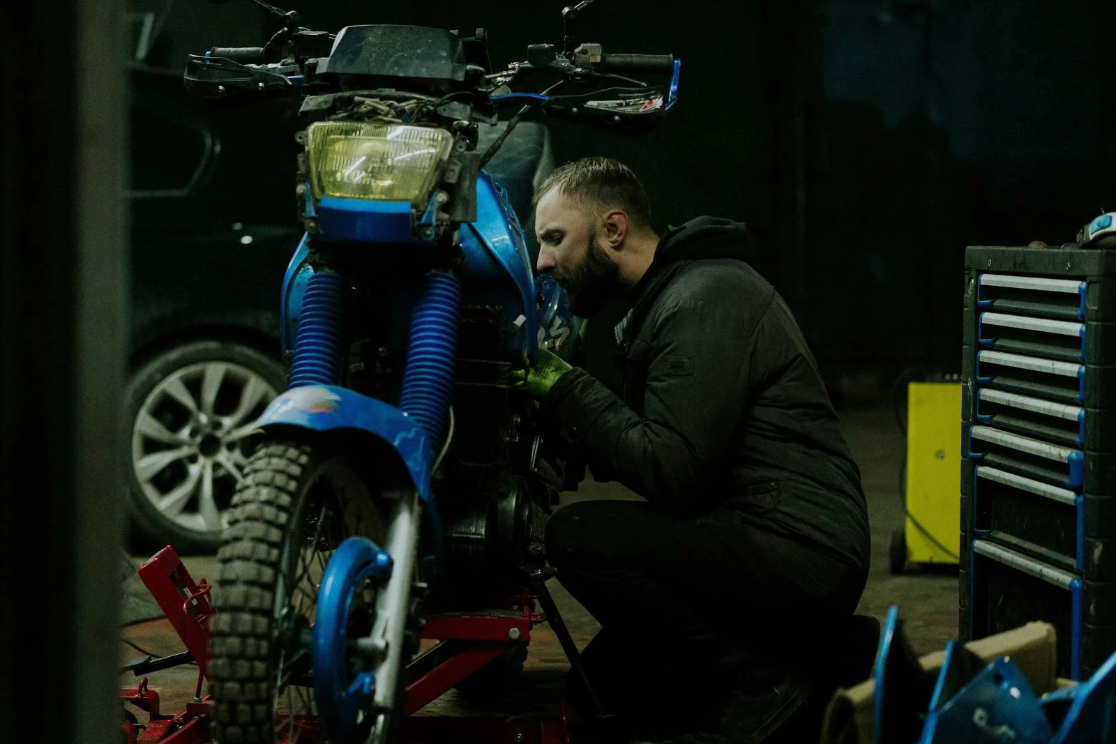 мужчина осматривает мотоцикл в гараже,  синий мотоцикл