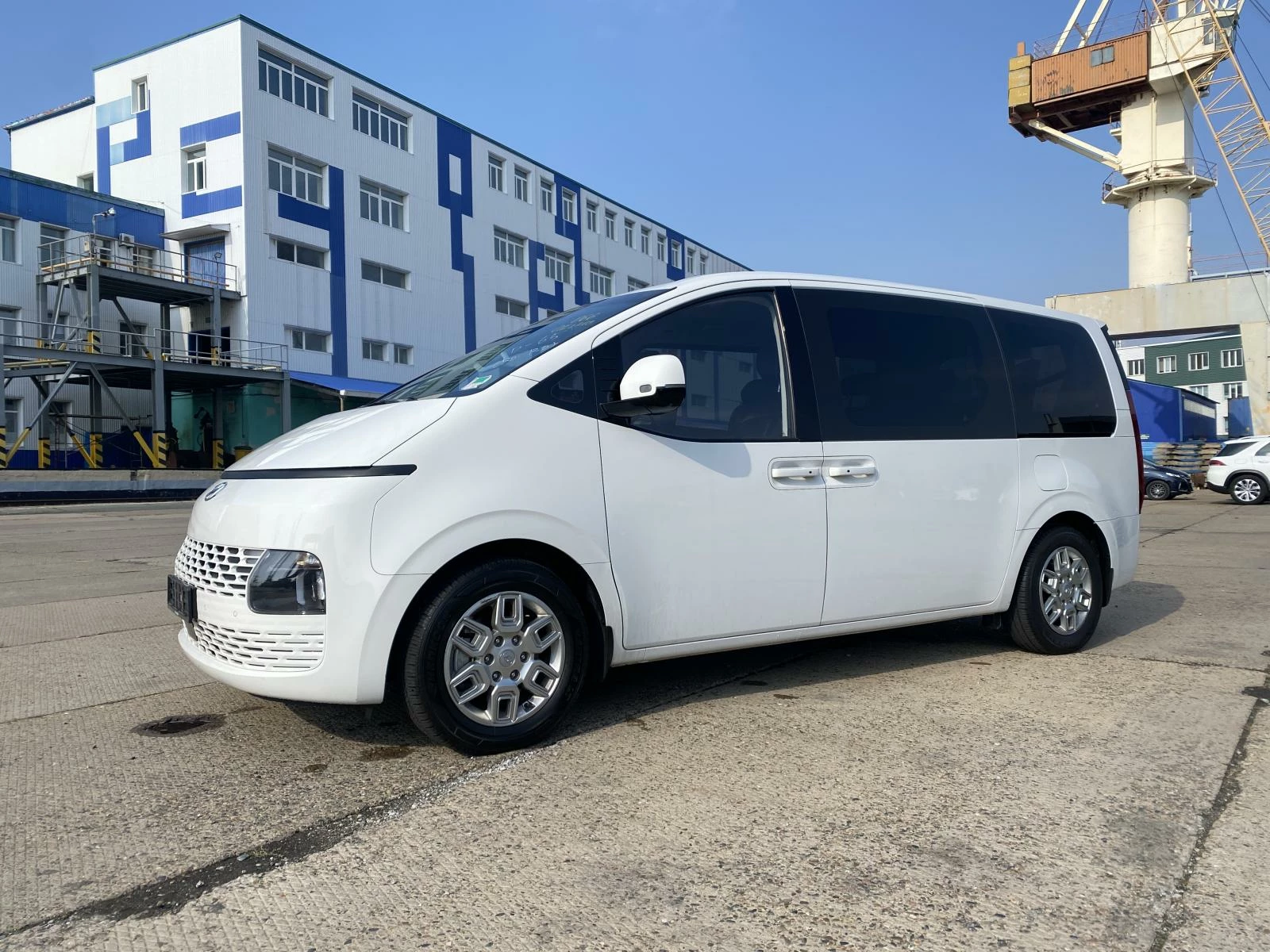 Hyundai Staria US4 белого цвета 2022 год 2,2 турбо вид сбоку на фоне порта и голубого неба
